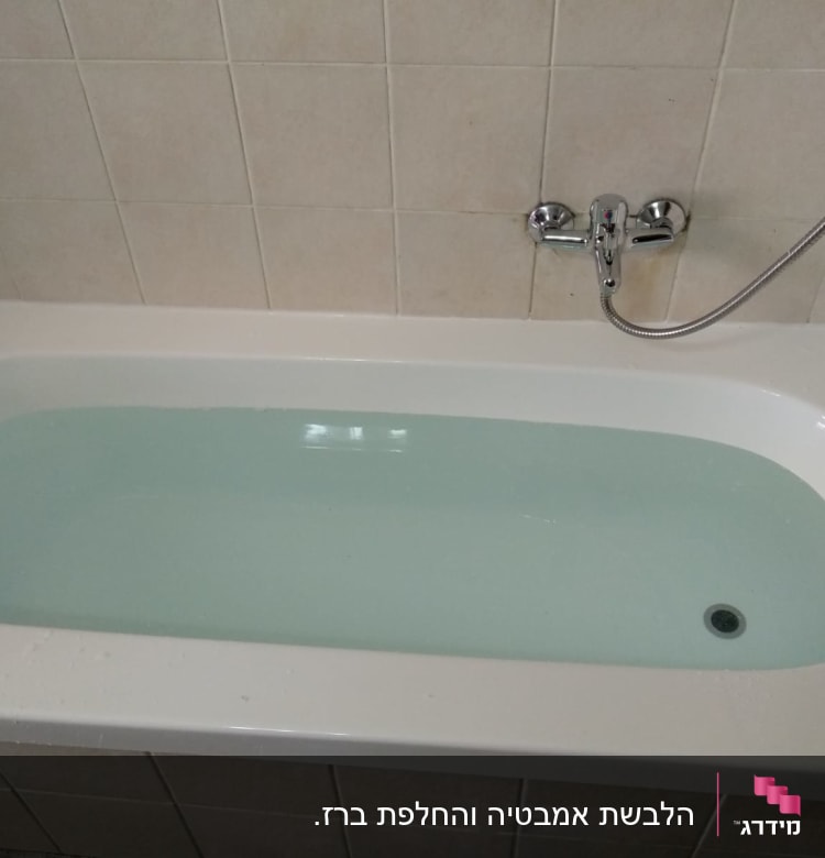 אמבטיה מלאה מים עם ברז וכיסוי קיר קרמיקה